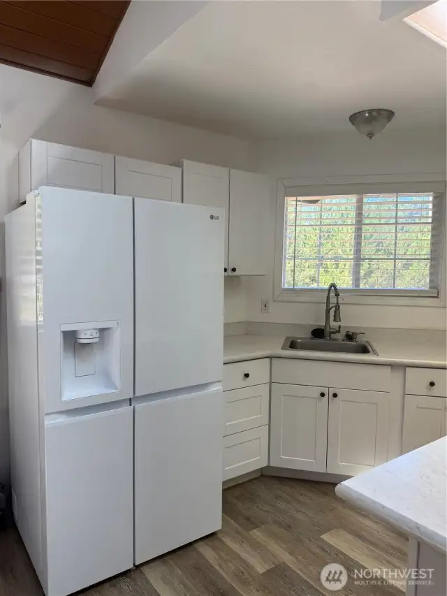 Large refrigerator. Note wood laminate flooring throughout the home except bedrooms.