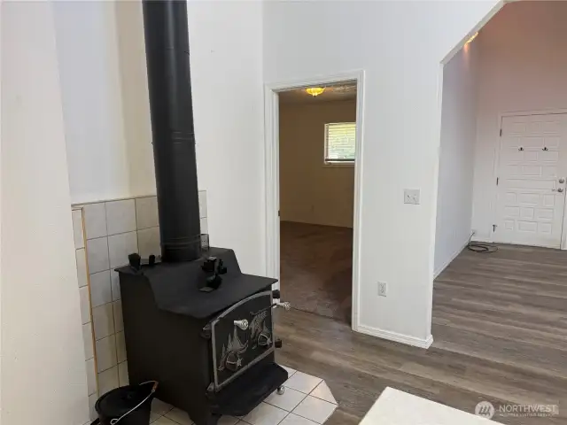 Wood stove and looking into the primary suite with carpeting.