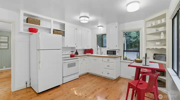 Large windows fill the kitchen with natural light and lush green views.