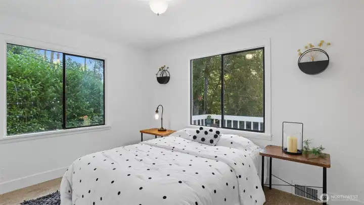 Bright primary retreat with dual windows framing private green views.