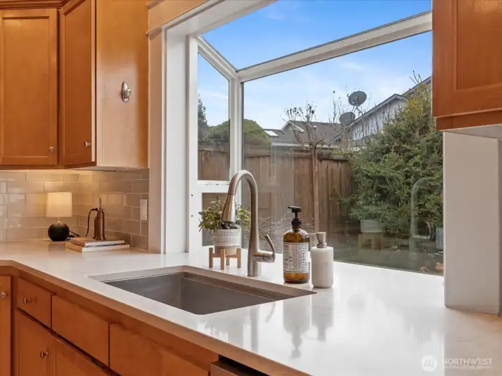 Garden window highlights view of the waterfall and private backyard.