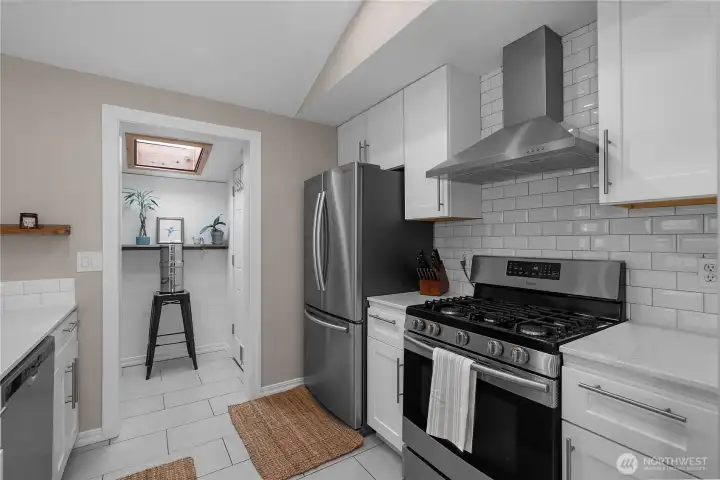 Clean white cabinetry, subway tile, and adjacent pantry give this kitchen a fresh, functional feel.