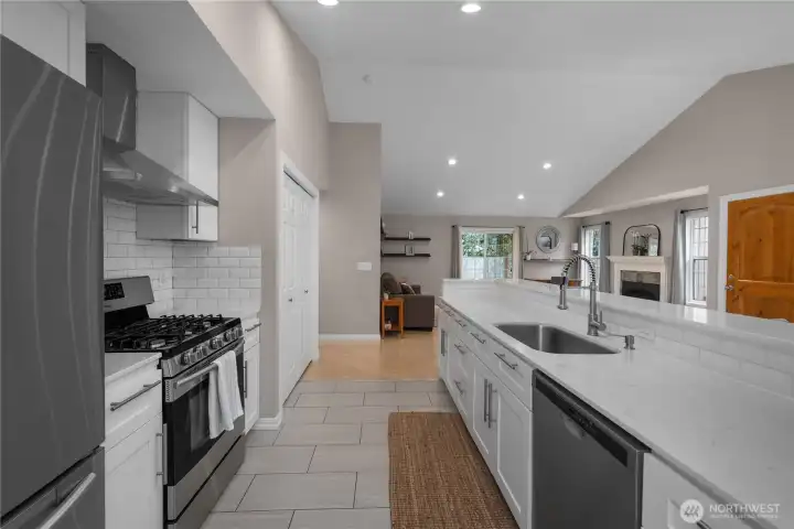 Long quartz counters, bar seating, and open sightlines create a bright, connected kitchen layout.