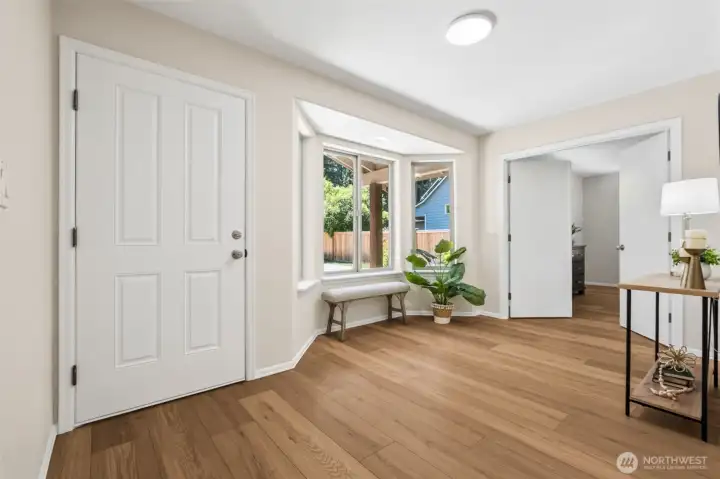 Step inside to a light-filled foyer featuring new warm LVP flooring, a charming window seat area, and expansive picture windows that bring the outdoors in and create an inviting first impression.
