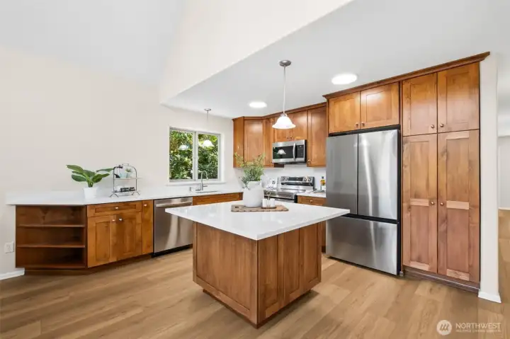 The beautifully updated kitchen is designed for gathering, featuring rich wood cabinetry, gleaming quartz countertops, a center island, and abundant storage.