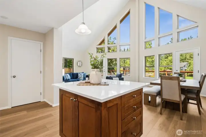 The addition of a new quartz center island overlooks the spectacular great room and dining area, where soaring ceilings and a dramatic wall of windows fill the home with natural light and showcase picturesque views of the deck, creek, and surrounding greenery. A spacious island with quartz countertops provides the perfect gathering spot for casual meals and entertaining.