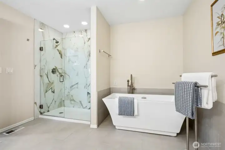 Pamper yourself in the beautifully appointed primary bath featuring a freestanding soaking tub, spacious step-in shower with elegant marble-inspired surround, frameless glass enclosure, and a serene, spa-like ambiance.