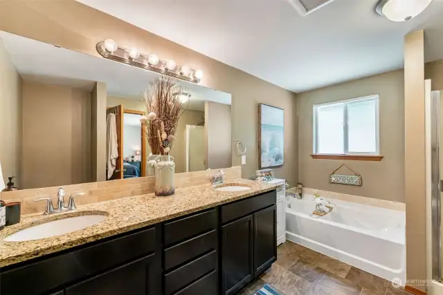 The primary bedroom's private bath features a granite countertop, a soaking tub and a separate shower. Your own private spa for relaxing after a long day.