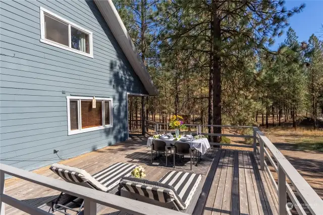 Large wood deck on south side of this home overlooks Pine tree landscape.