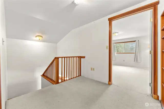Upper Loft nook leads to Primary bedroom. Carpeted. Wood trim throughout. Built in bookshelf. Extra Bonus 3rd bedroom across from Primary.