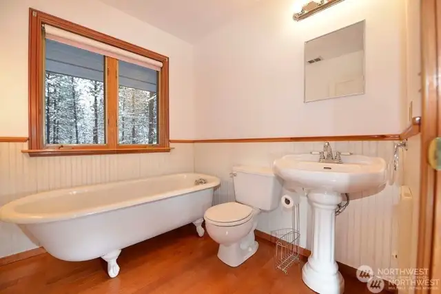 Classic Clawfoot tub and pedestal sink bath main floor. Hardwood floor.