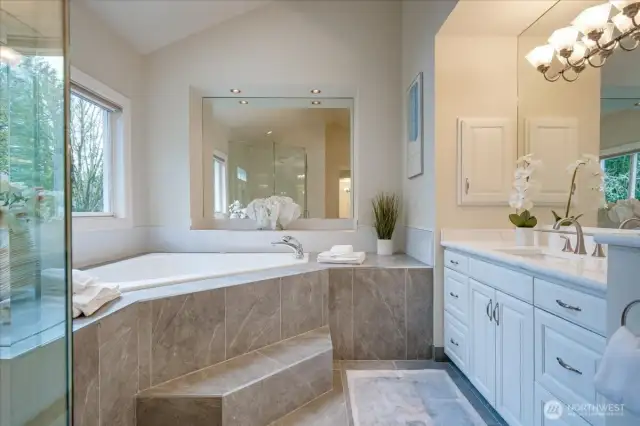 Uplifting and updated 5 piece bathroom with designer tiled floor and shower, 2-person jetted tub, make-up vanity, crisp white cabinetry with separate quartz vanities.