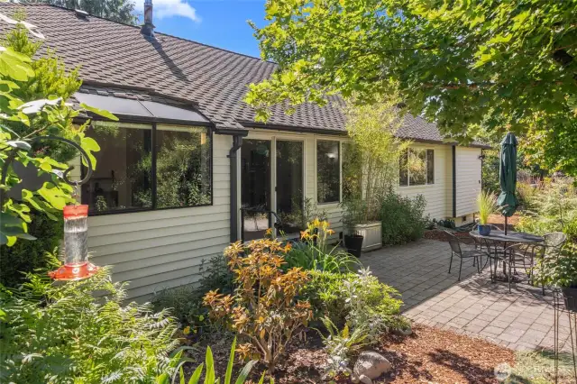 Exterior back with luscious landscaping and newer patio pavers