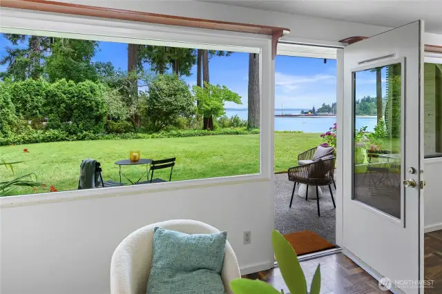 Living room door opens to the patio and lush green grass common area