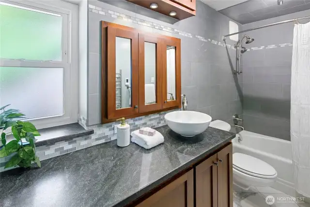 The updated and luxurious bath with cherry cabinetry, radiant heated floors and a wall mount towel warmer