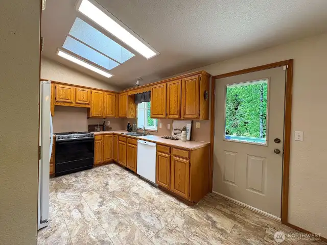 Functional kitchen just off the dining room, with oak cabinetry and garden window framing backyard views.