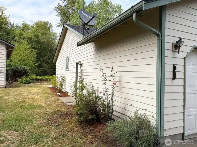A colorful row of rose bushes adds timeless charm and fragrance along the side of the home.