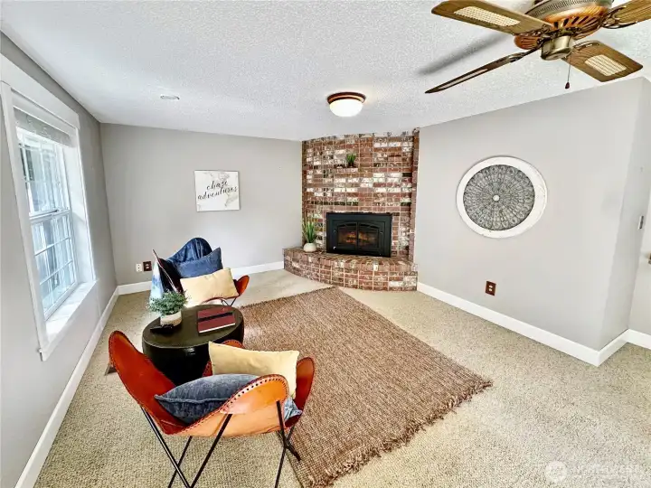 Generous family room with corner fireplace with gas insert, featuring brick surround.