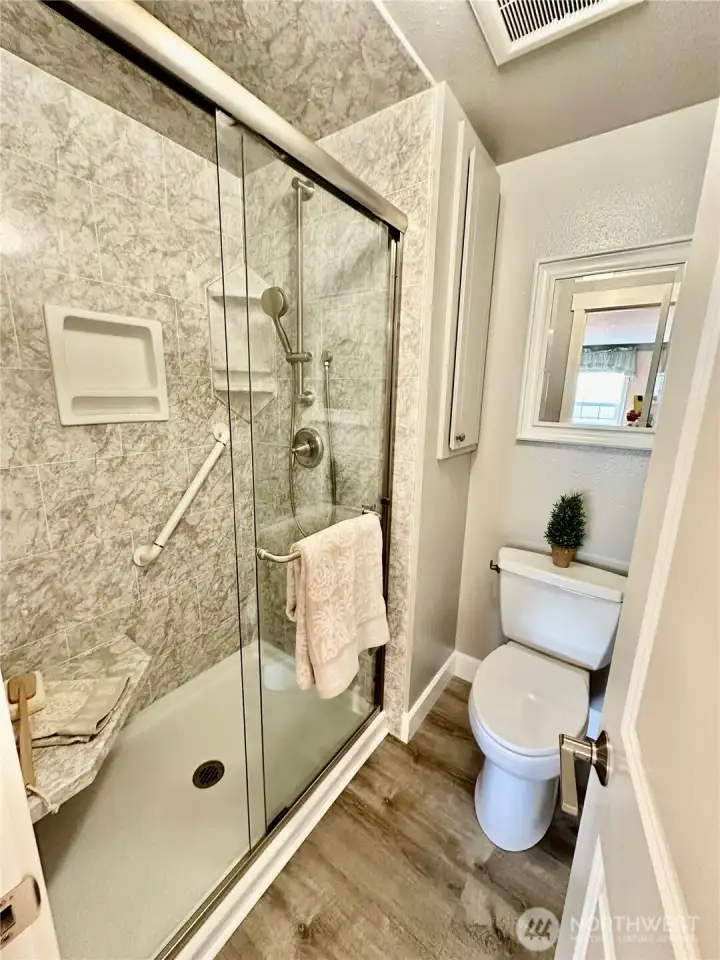 Primary shower/toilet area is updated.  Shower offers large seat and grab-bar.