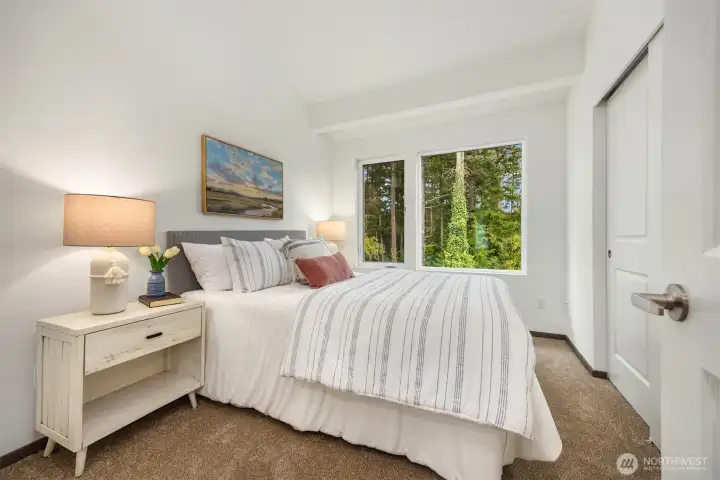 Primary bedroom with sizeable closet looks out to the forest views.