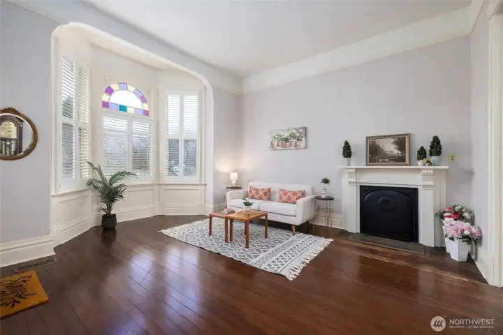 Elegant bay-window sitting room with classic fireplace.