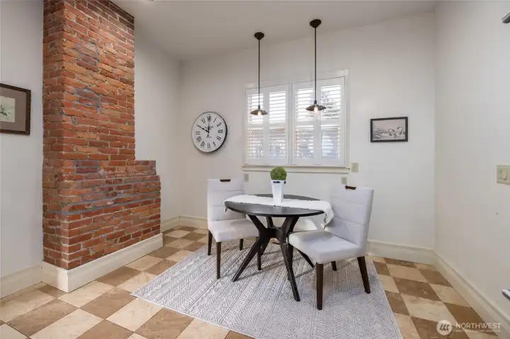 Breakfast nook beside exposed brick chimney.