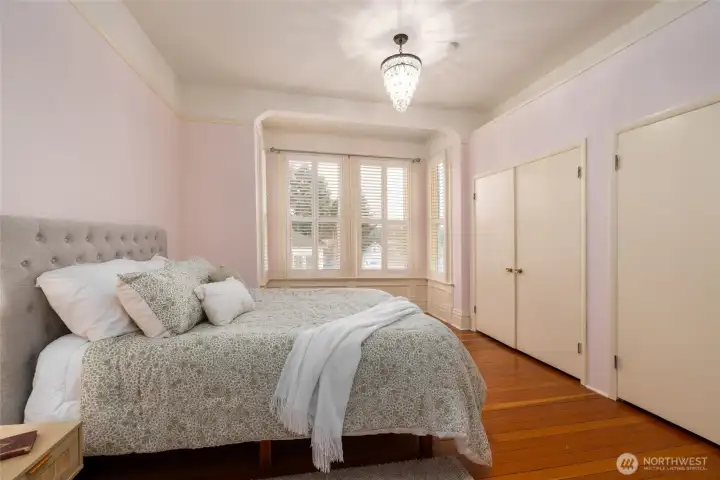 Bright bedroom with bay windows and chandelier.