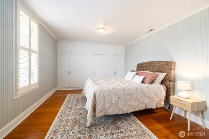 Bright bedroom with original wood floors and built in closets.
