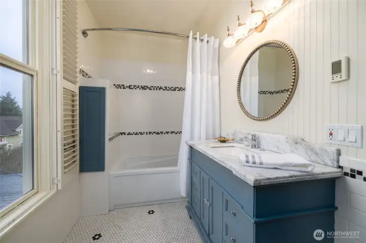 Classic tiled bath with blue vanity and tub/shower.