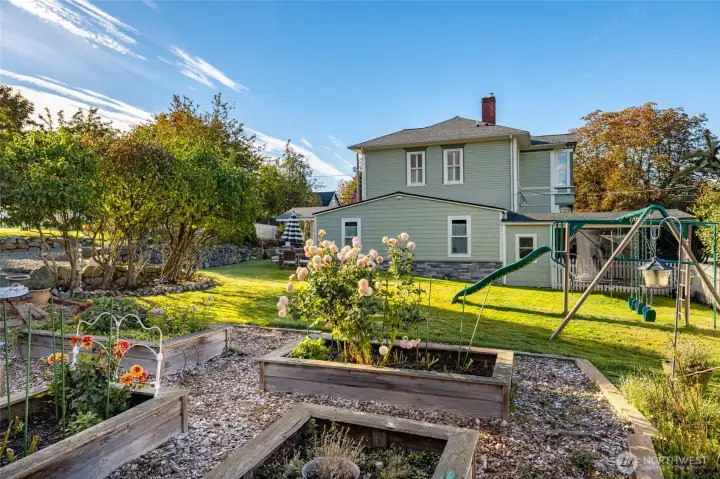 Sunny yard with raised garden beds and playset.