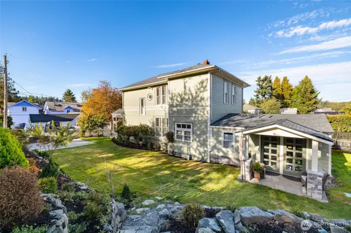 Sunny side yard with stone wall and patio chair.