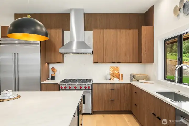 Designed for connection and culinary creativity, this kitchen includes a wine fridge, high-end Subzero and Wolf appliances, a six-burner stove, and exquisite Belmont cabinets