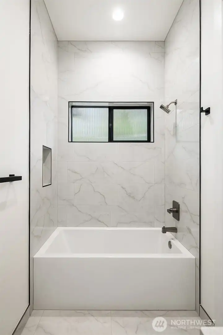 The guest bathroom showcases exquisite tilework that extends all the way to the ceiling, elevating the aesthetic.
