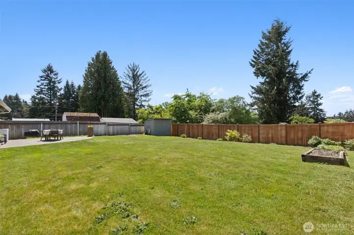 The spacious backyard is fully fenced and has a shed and raised flowerbeds.