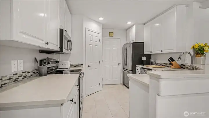 Light and bright kitchen with new vinyl plank flooring, stainless appliances and walk in pantry