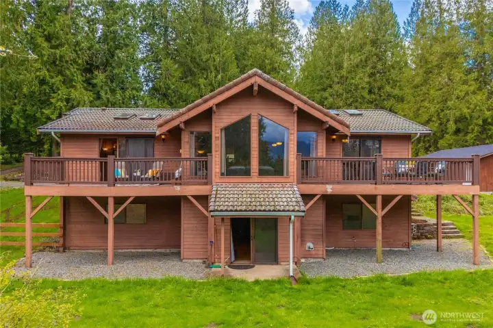 Rear view of house shows daylight basement exit and two private upper decks that overlook the forest and mountain views.