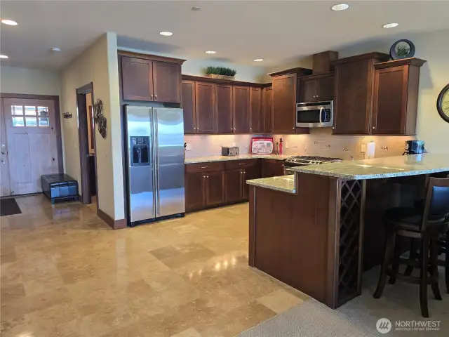 Large kitchen has granite slab counters, undercounter lighting