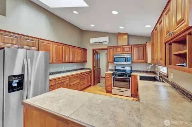 Light and bright kitchen with vaulted ceilings, custom cabinetry, hardwood floors, and stainless steel appliances.
