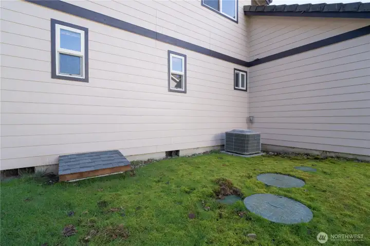 Side of home with crawl space access, AC unit, and septic lids