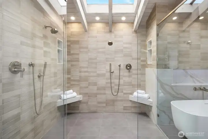 A true spa retreat—smooth, continuously heated floors tapered to a wall drain, a sculptural solid-stone soaking tub, dedicated gas hot water, and LED-accented defrosting mirrors.