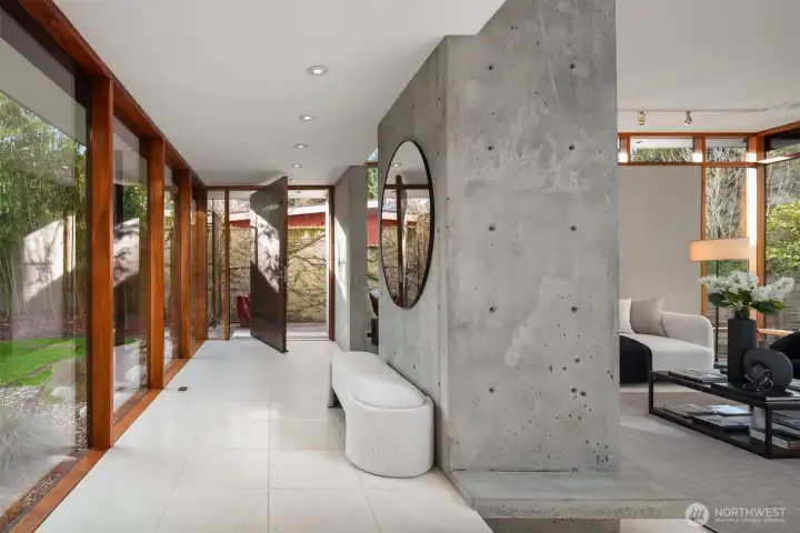 The entry itself is an architectural moment. A reclaimed Douglas fir pivot door provides tactile contrast to sleek, radiant-heated limestone floors—an immediate signal that this home is both design-forward and deeply livable.  Once inside, the privacy is palpable: gallery-like spaces fill with natural light, while walnut-wrapped walls of glass open the home to its serene, park-like surroundings—expanding the sense of space and dissolving the boundary between architecture and landscape.