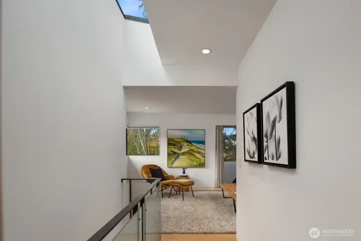The home’s flow continues upward and downward with equal intention. The floating staircase—washed in natural light from above—creates a striking vertical moment, while a dramatic skylight shares daylight across all three levels, keeping the entire home bright and cohesive.