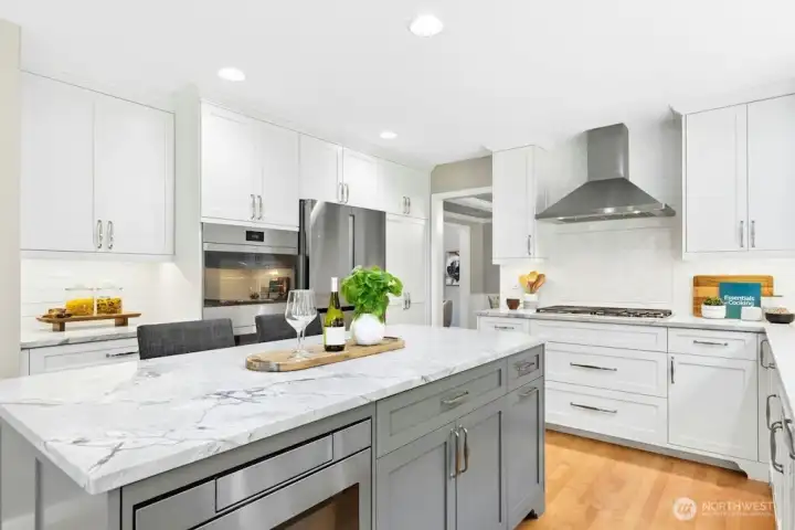 Stainless steel appliances feature Wolf double smart ovens, a Bosch refrigerator, Wolf gas stove top, and an in-island microwave!