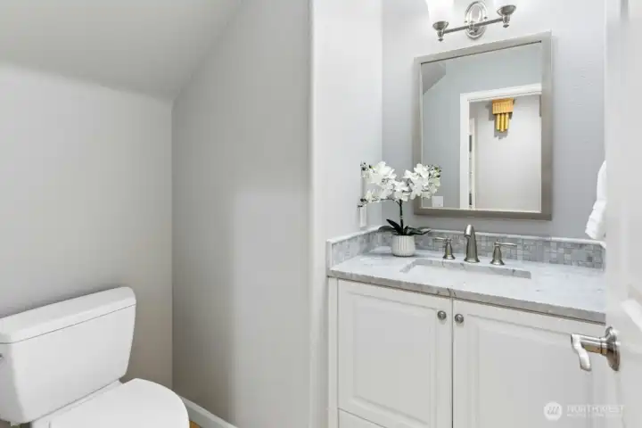 Fully remodeled powder room with marble counters and natural stone flooring