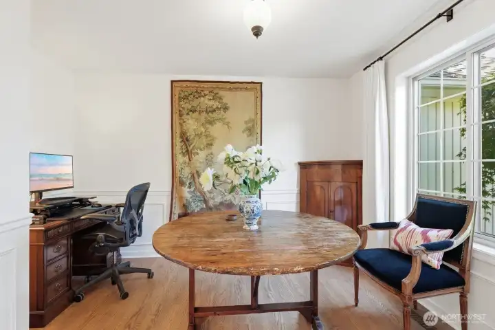 The office off the foyer through French doors with wainscoting and hardwood floors.