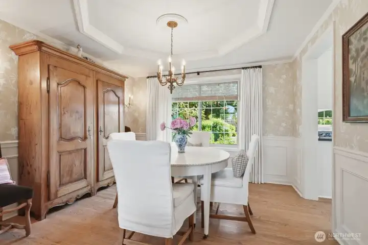 The adjacent formal dining room features wainscoting, double crown molding and hardwood floors.