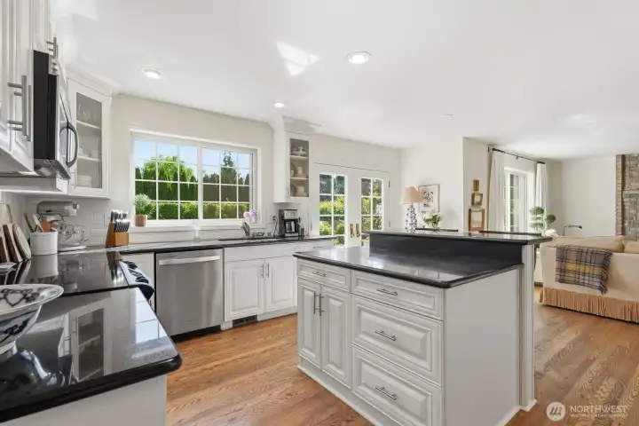 Updated kitchen with custom white cabinetry, slab granite counters and stainless appliances.