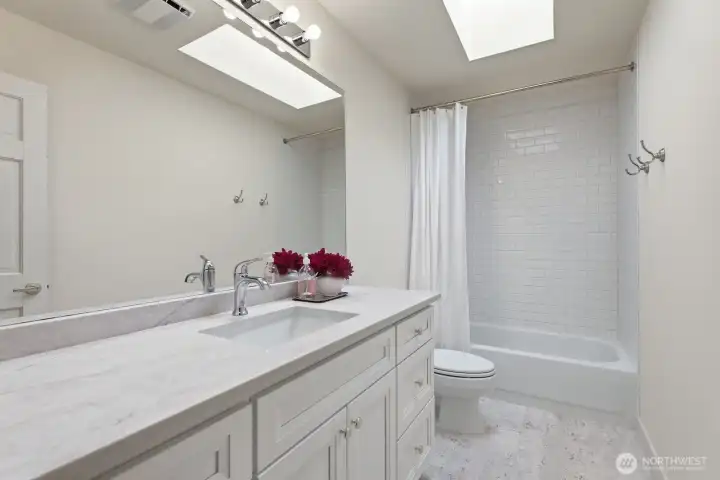 A newly updated hall bath with limestone flooring, quartz countertop, vanity and subway tiled tub/shower.