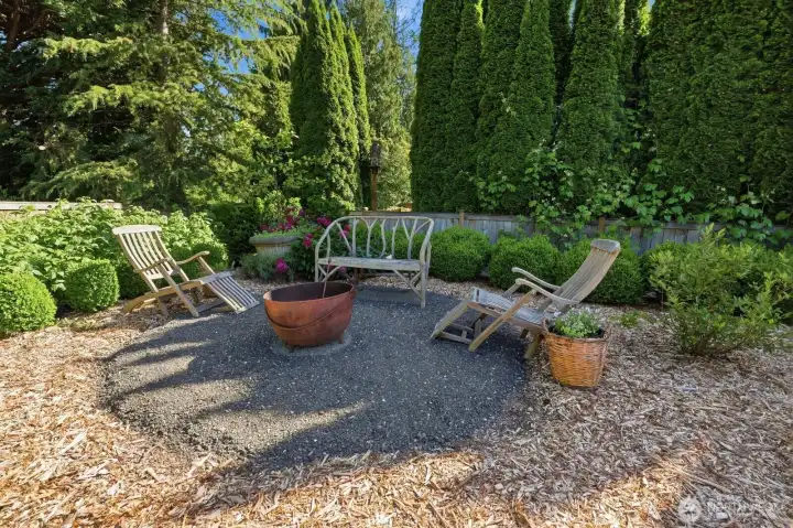 Cozy fire pit surrounded by lush gardens.
