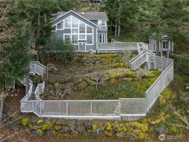 250 Switchback Rd. Nestled amongst the trees on the hillside. Front view of home, deck with hot tub, garden shed, terraced and fenced in fruit trees (and a beautiful Madrona)